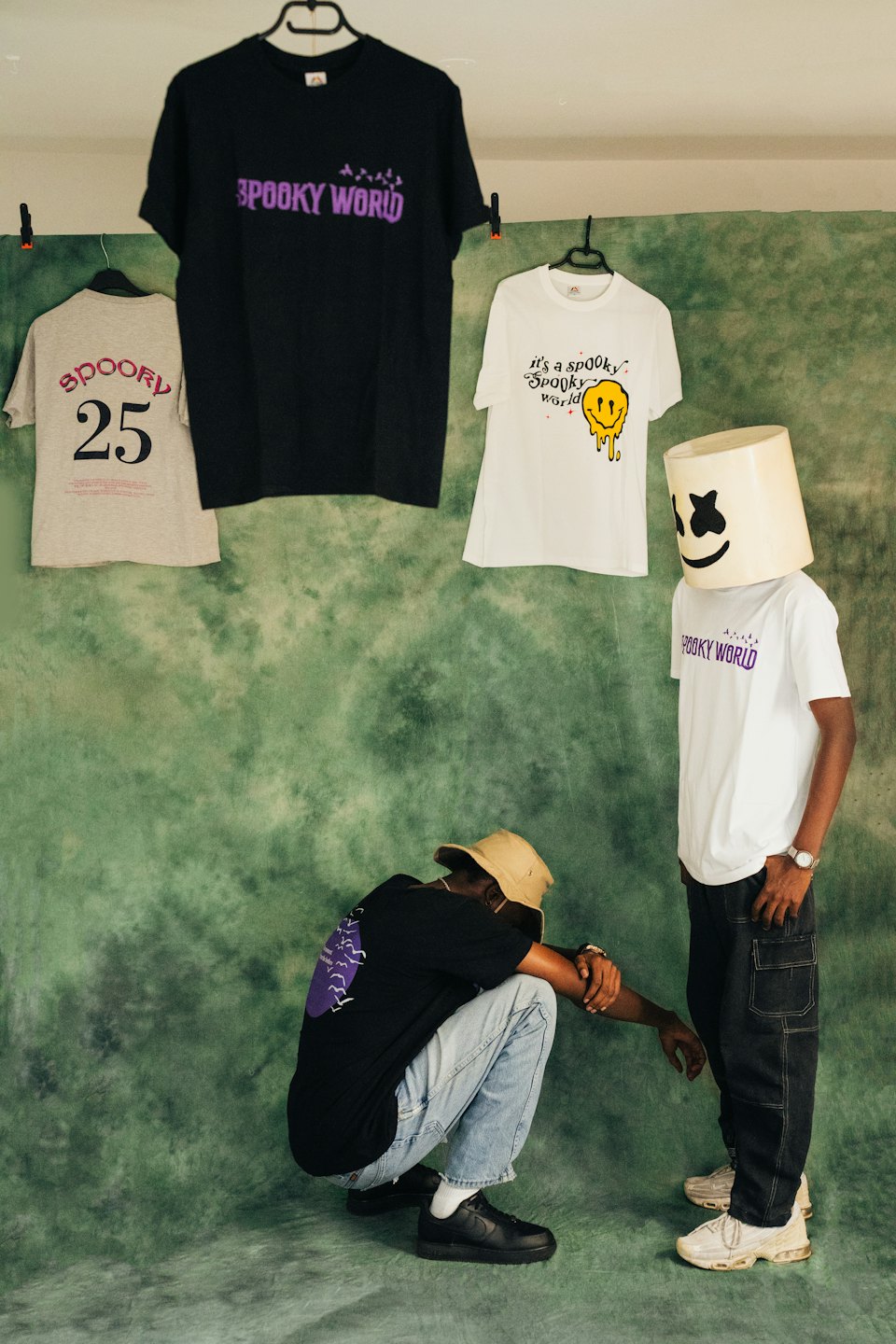 Two people model graphic t-shirts in front of clothing racks.