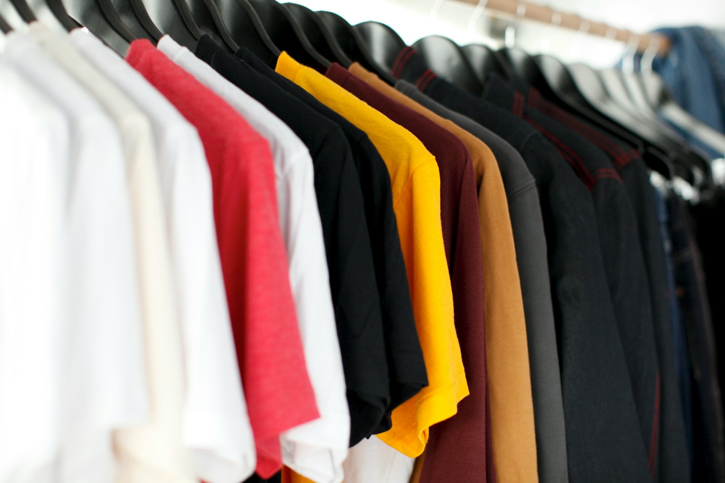 Colorful t-shirts and long-sleeved shirts displayed on hangers.
