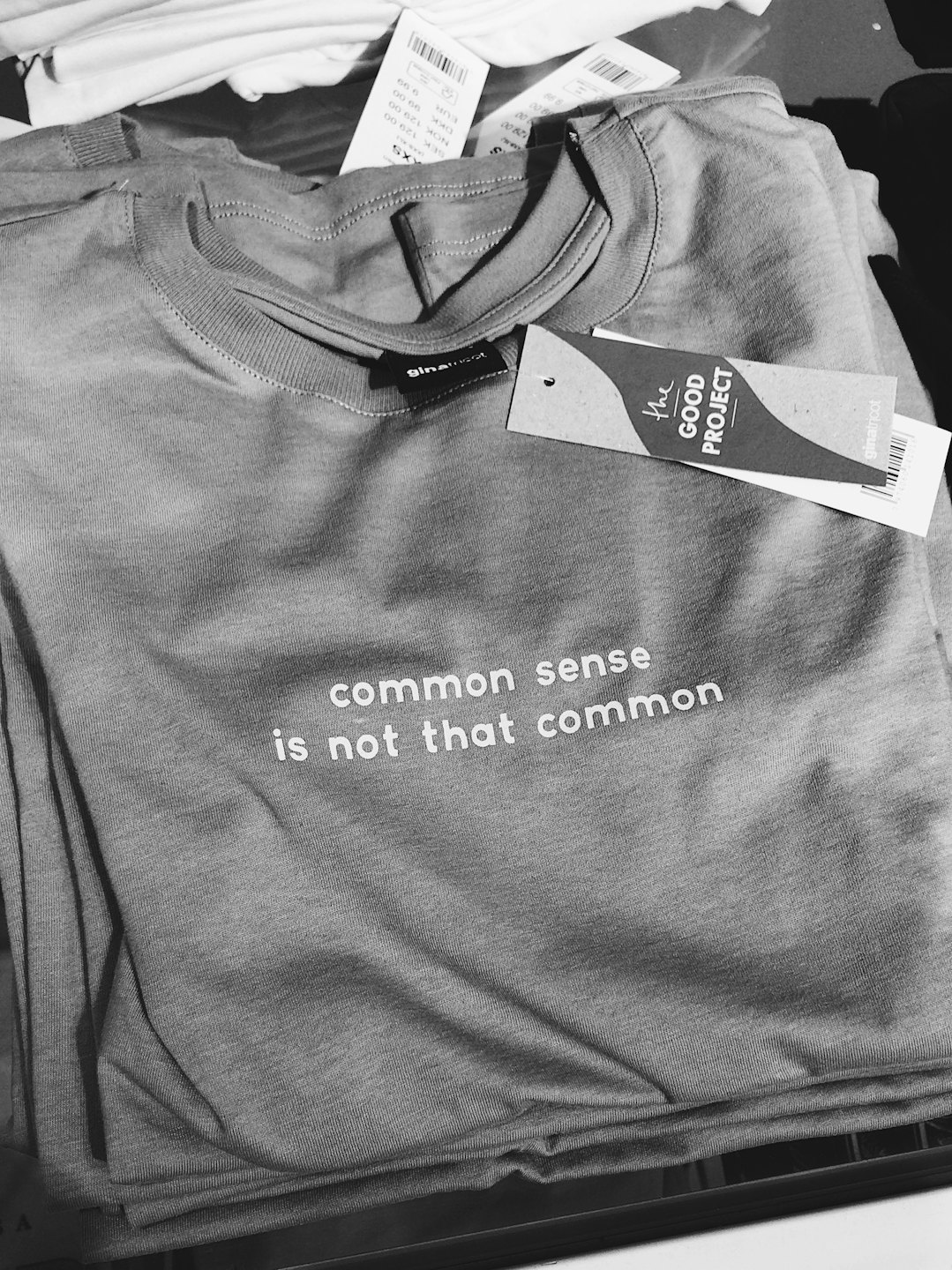 Folded grey t-shirt with text displayed in a shop.